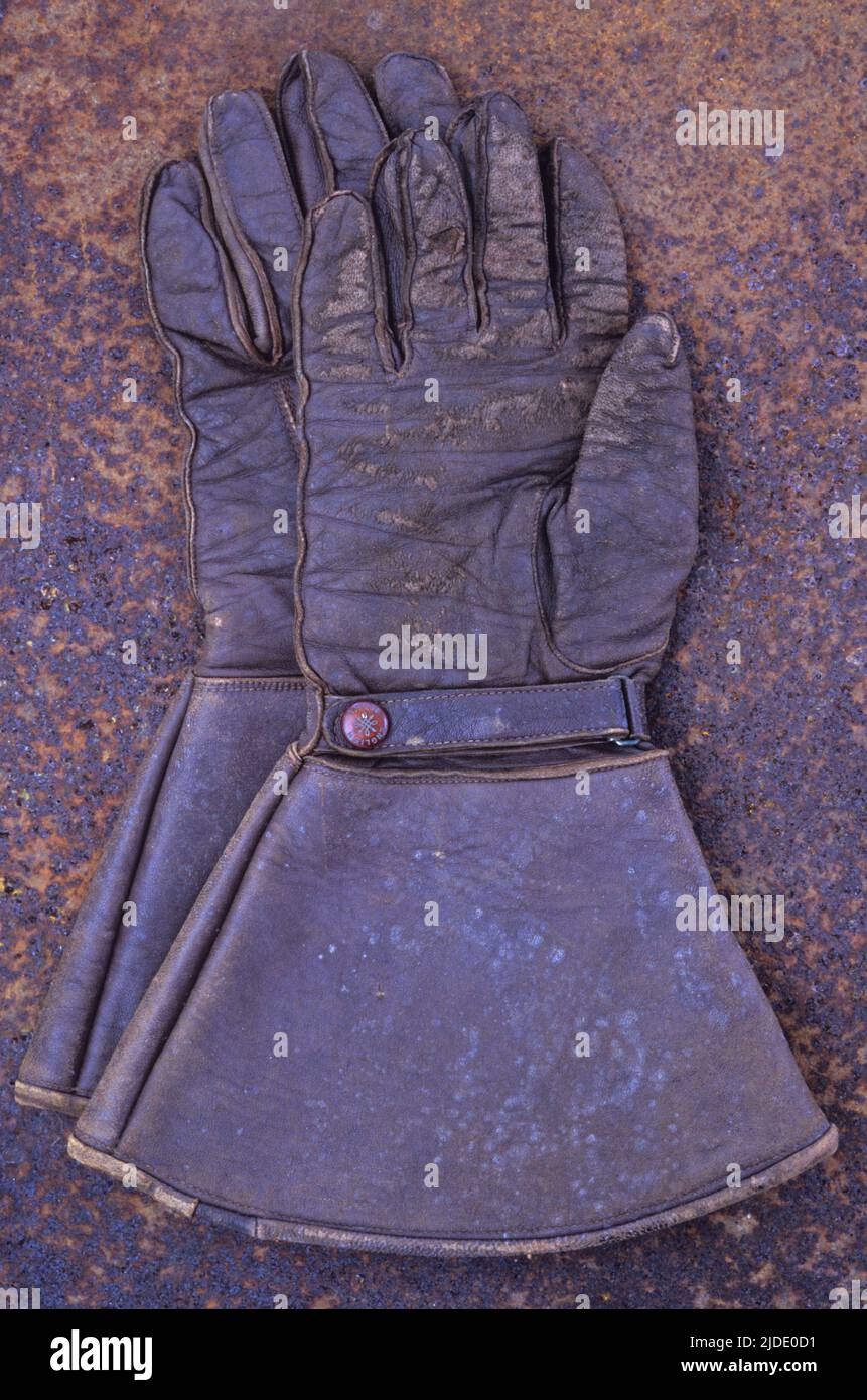 Pair of vintage brown leather gauntlets or large gloves lying on rusty metal sheet Stock Photo