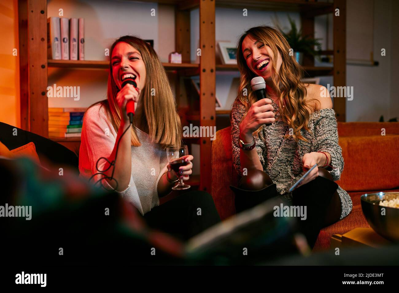 Girls having fun at karaoke night at home. Stock Photo