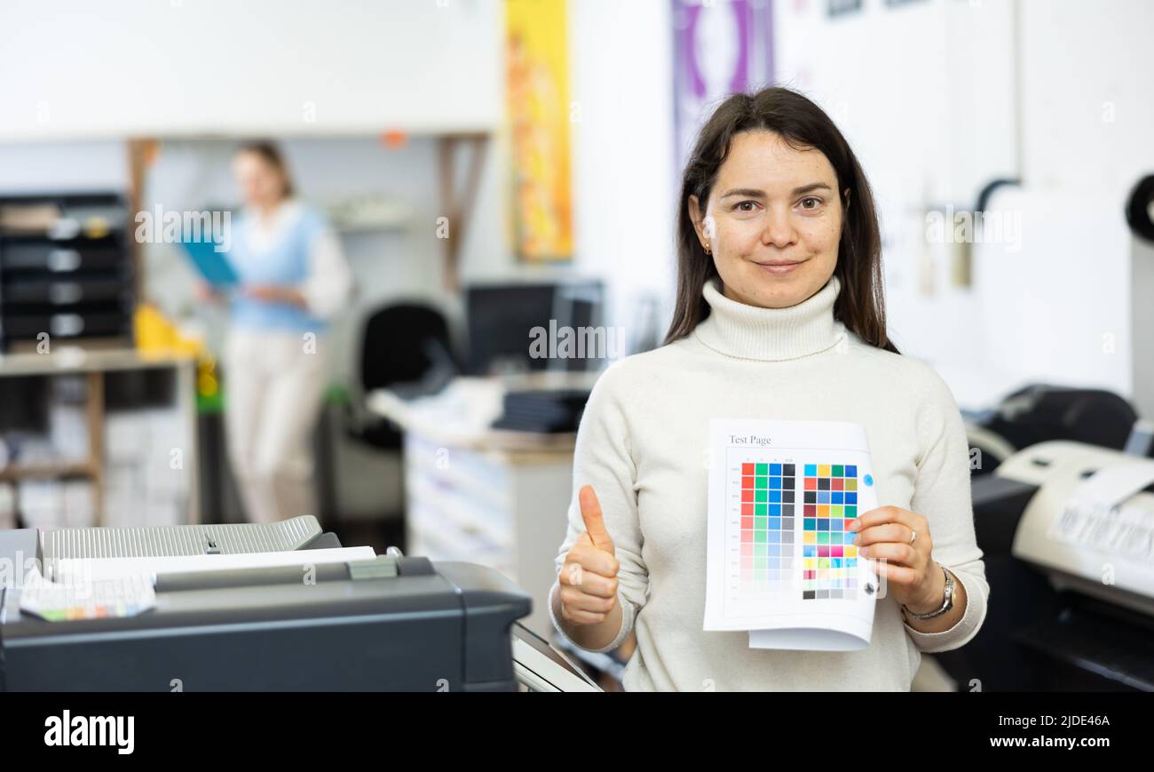 Positive woman publishing facility worker with colour test page Stock Photo