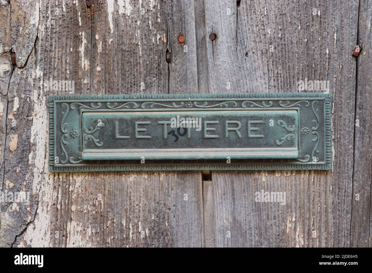 Ornate letter box on an old rustic sun bleached wooden door, Gozo Stock Photo
