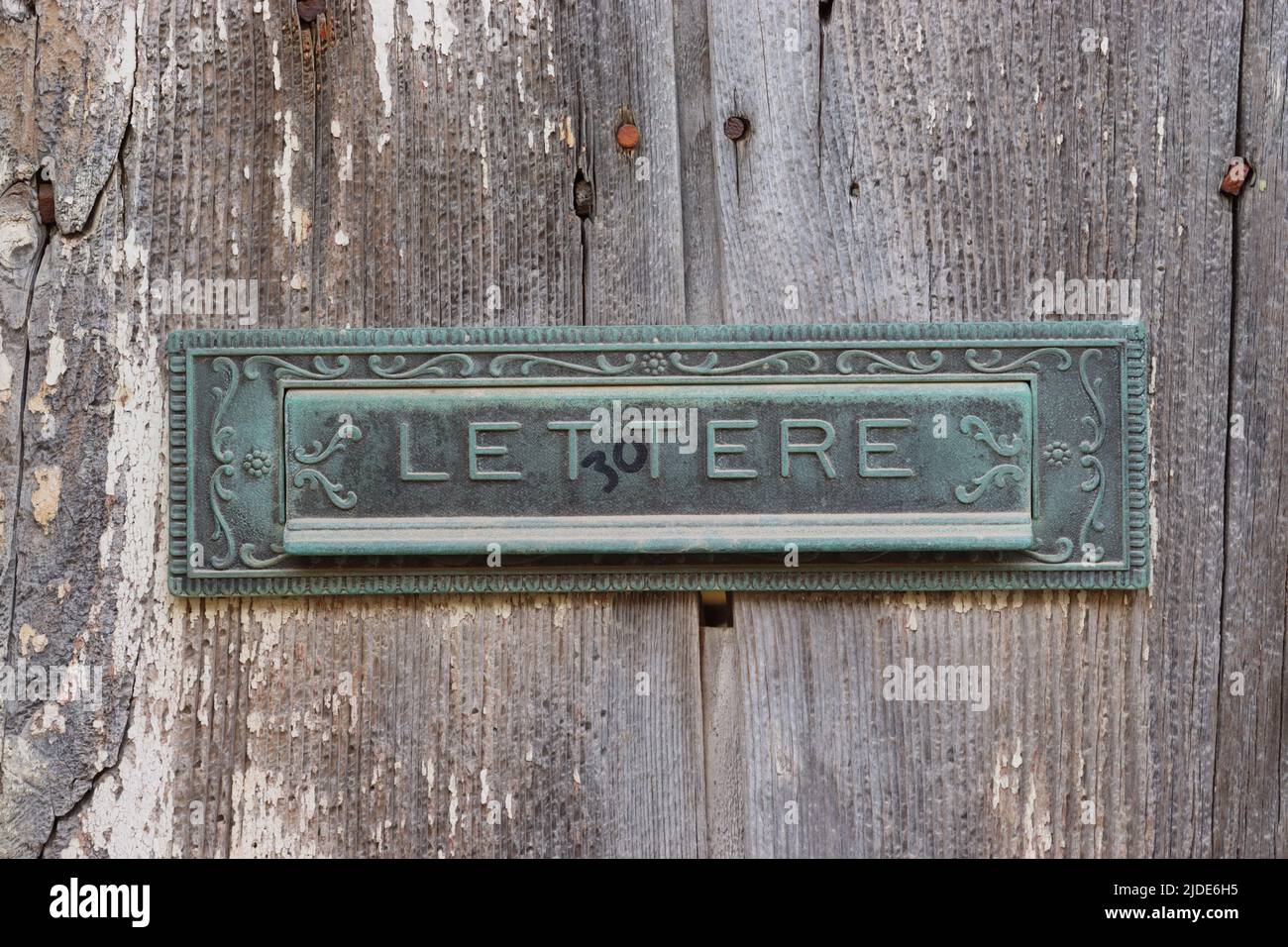 Ornate letter box on an old rustic sun bleached wooden door, Xaghra