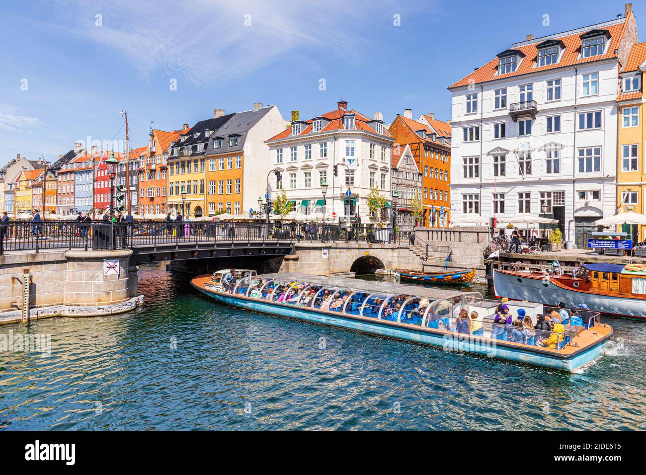 A tourist tour boat passing Nyhavn, the colourful 17th-century canal waterfront in Copenhagen, Denmark. Stock Photo