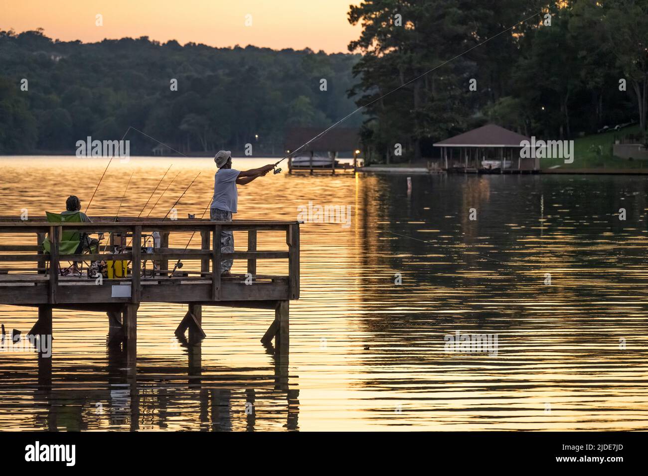 Couple fishing from a fishing dock at sunset on Lake Oliver, a reservoir above Oliver Dam between Columbus, Georgia and Phenix City, Alabama. (USA) Stock Photo