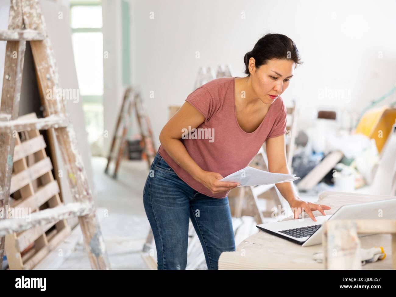 Woman construction manager checking project documentation, using laptop Stock Photo