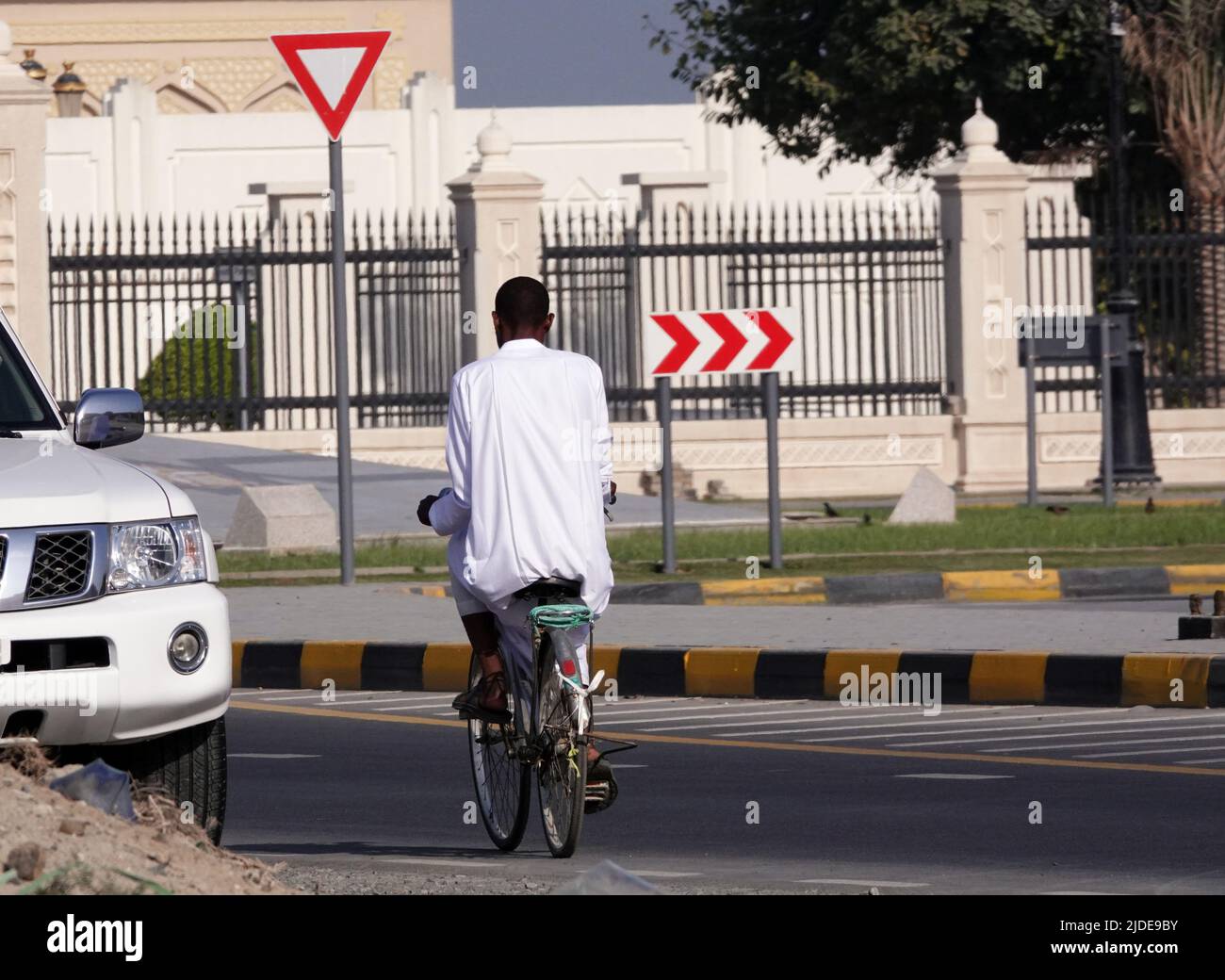 Sharjah, UAE February 21, 2020: A man in national dress rides a bicycle. Stock Photo