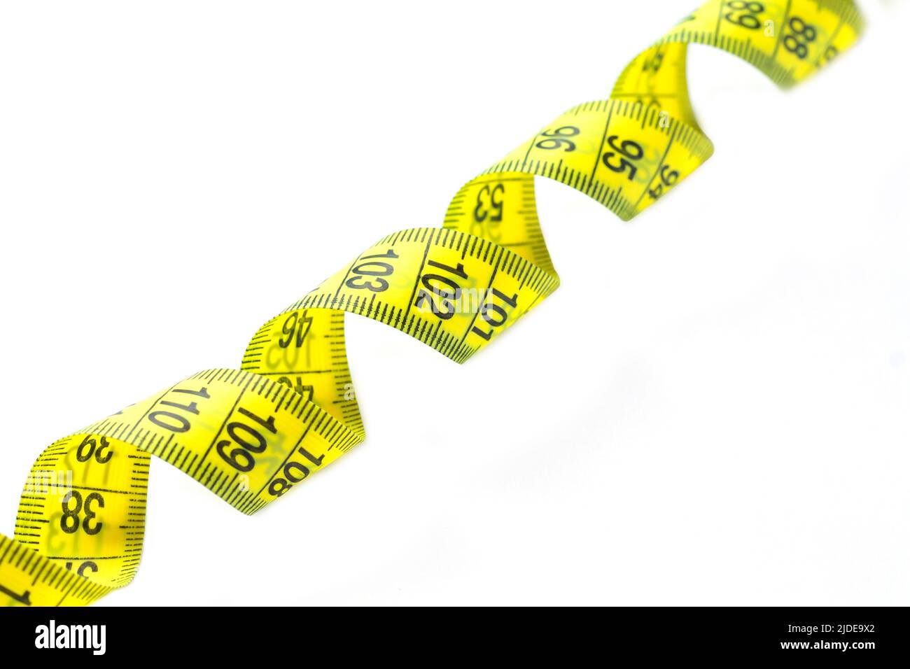Spiral of yellow and black measuring tape isolated on white background close-up Stock Photo