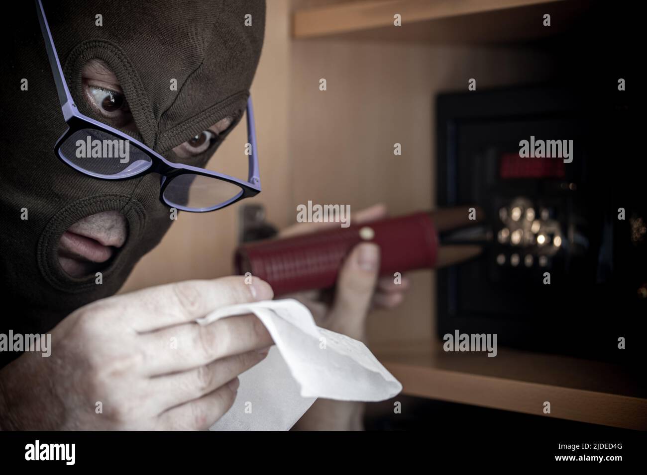 The man in the mask reads a hint instructions for opening the safe