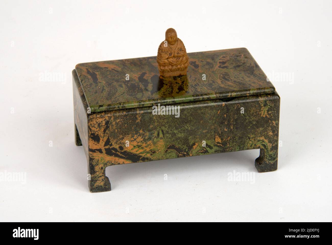 A selection of bakelite and plastic items.  Ebena three-part trinket box with a Buddha figure on the lid with gold-leaf detail. Stock Photo