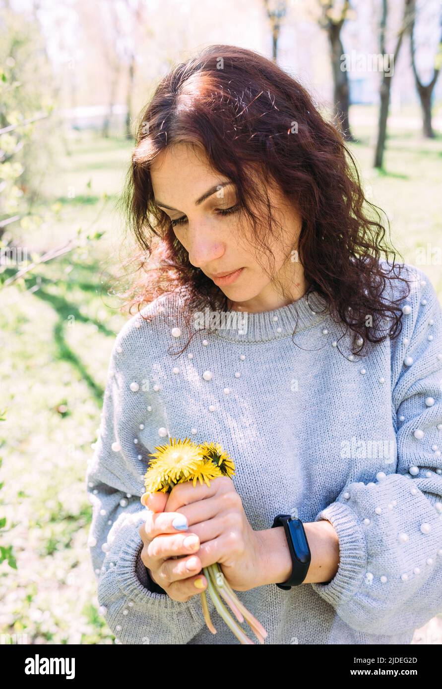 Portrait of a young brunette woman in spring in a park with dandelions Stock Photo