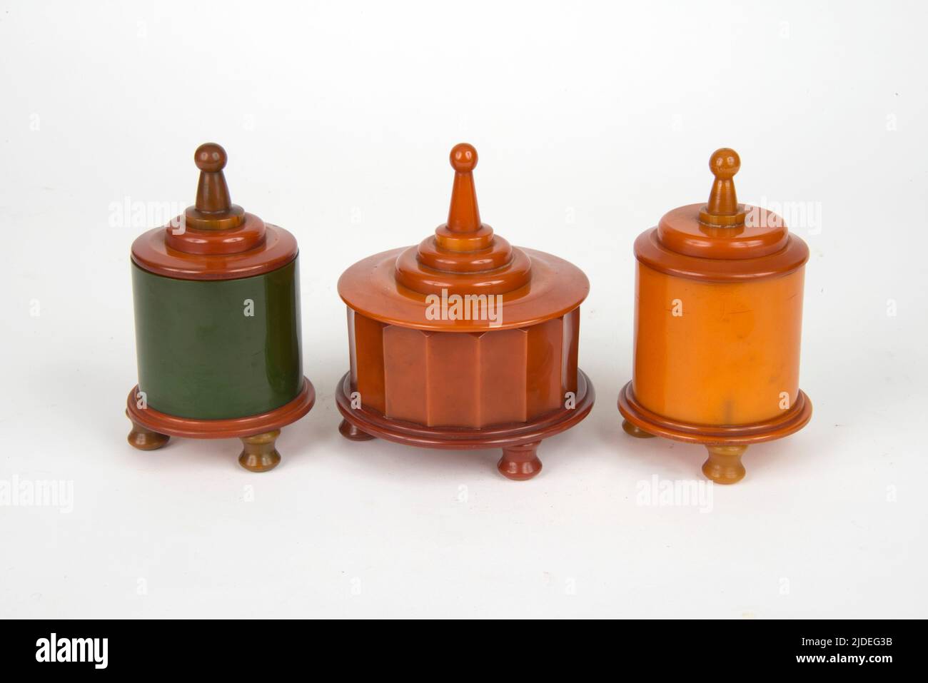 A selection of bakelite and plastic items. Group of Art Deco cast phenolic faceted pots with tapered stepped lids, the middle one is a music box Stock Photo