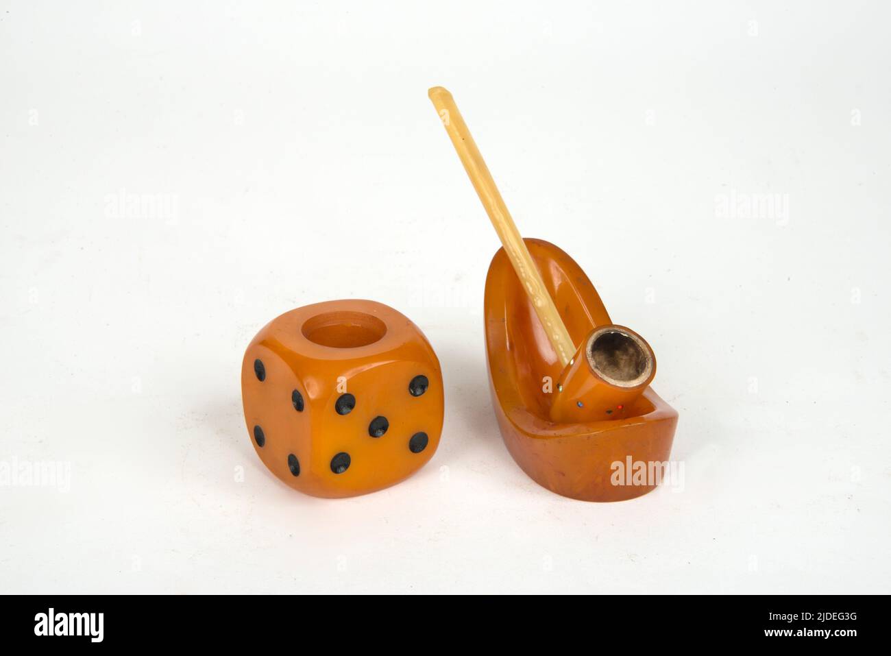 A selection of bakelite and plastic items.  Large novelty dice-shaped ash-tray and and a1920's ladies 'Flapper' pipe with inset paste, pipe-stand in . Stock Photo