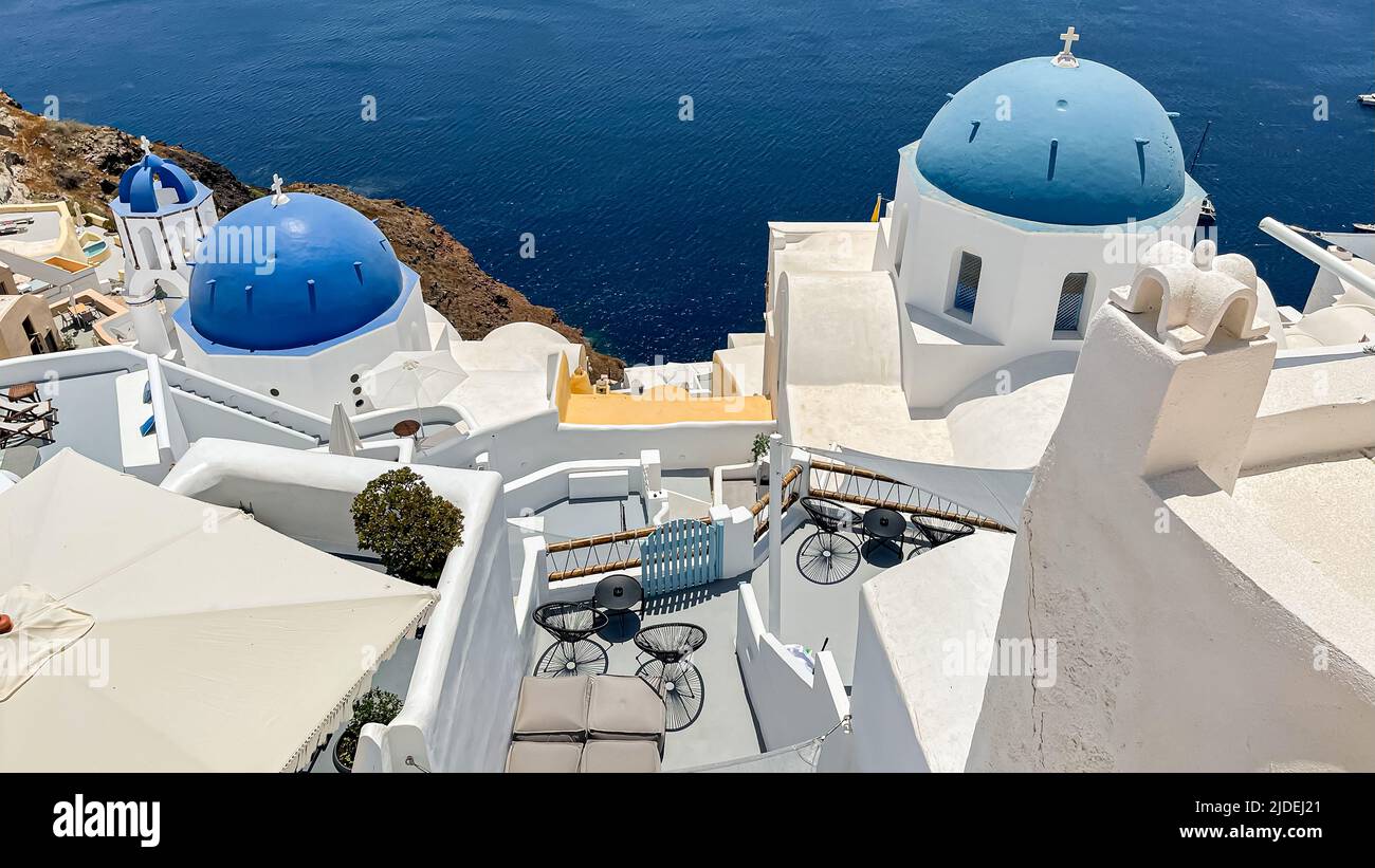 Looking down into the water over patios and blue church domes in iconic Oia on Santorini island Stock Photo