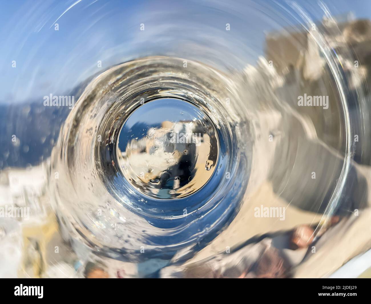 An unusual view of iconic Oia on Santorini island, seen through the bottom of a water glass Stock Photo
