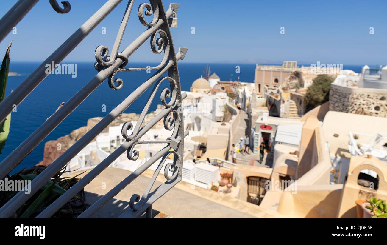 A view over the westermost part of iconic Oia on Santorini island through a cast iron fence with a shallow focus Stock Photo