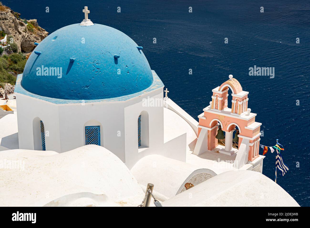 Blue church dome and pink bell tower in Oia Stock Photo