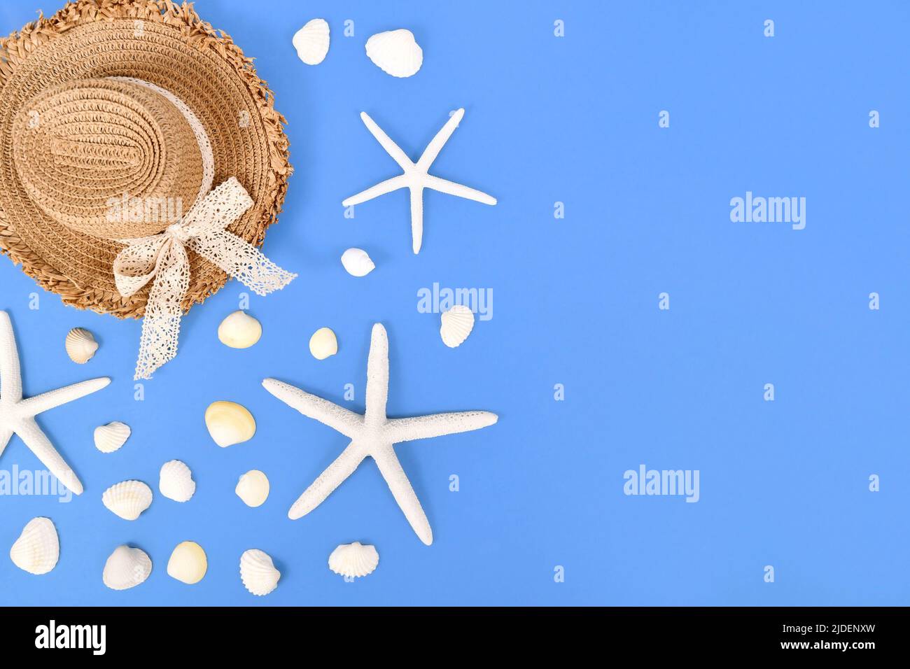 White starfish, seashells and summer straw hat on side of blue ...