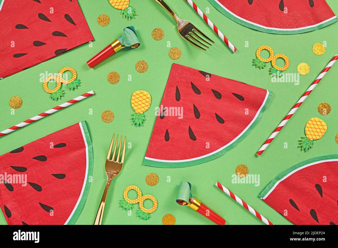Summer party flat lay with watermelon shaped napkins, drinking straws and confetti on green background Stock Photo