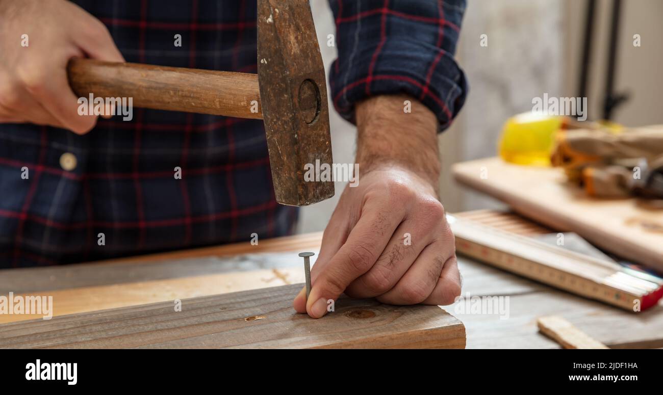 DIY, home repair and fix. Carpenter nail wood. Male hand hold hammer