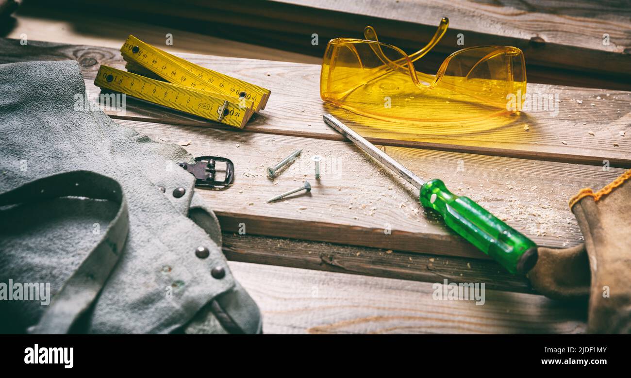 Work tool used and safety gear on wooden background. Construction industry. Hand tool old on wood, carpentry vintage equipment. Stock Photo