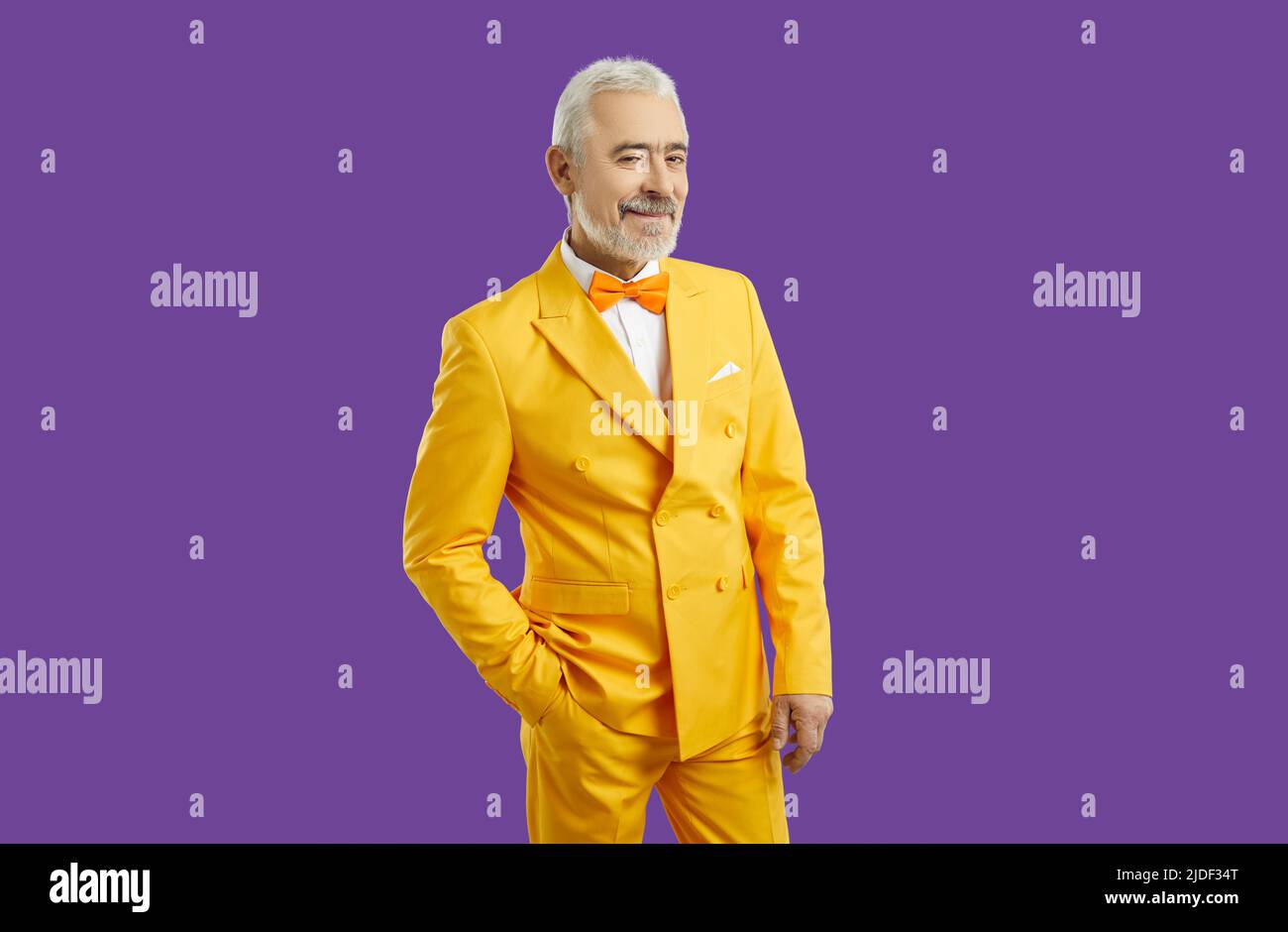 Handsome man wearing stylish yellow suit smiling at camera, happy and wealthy Stock Photo