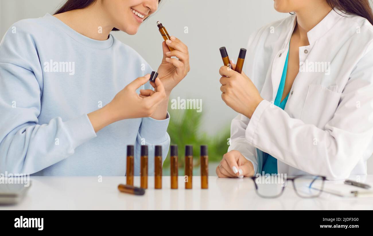 Happy women sitting in lab and smelling perfume samples or essential aromatherapy oils Stock Photo