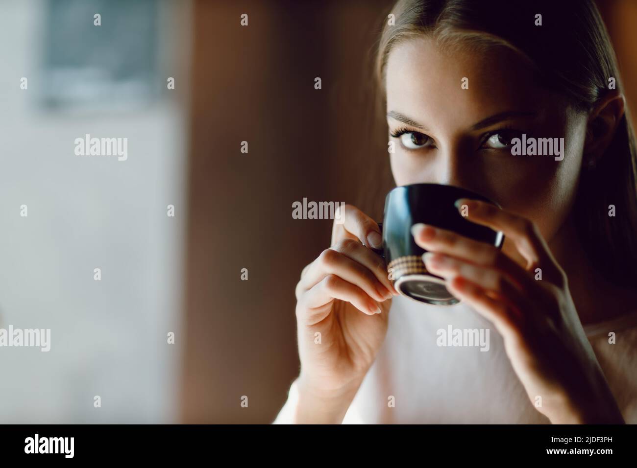 Young beautiful smiling woman enjoying drinking cappuccino coffee cup indoor cafe looking camera. Tea or coffee drink. Stock Photo