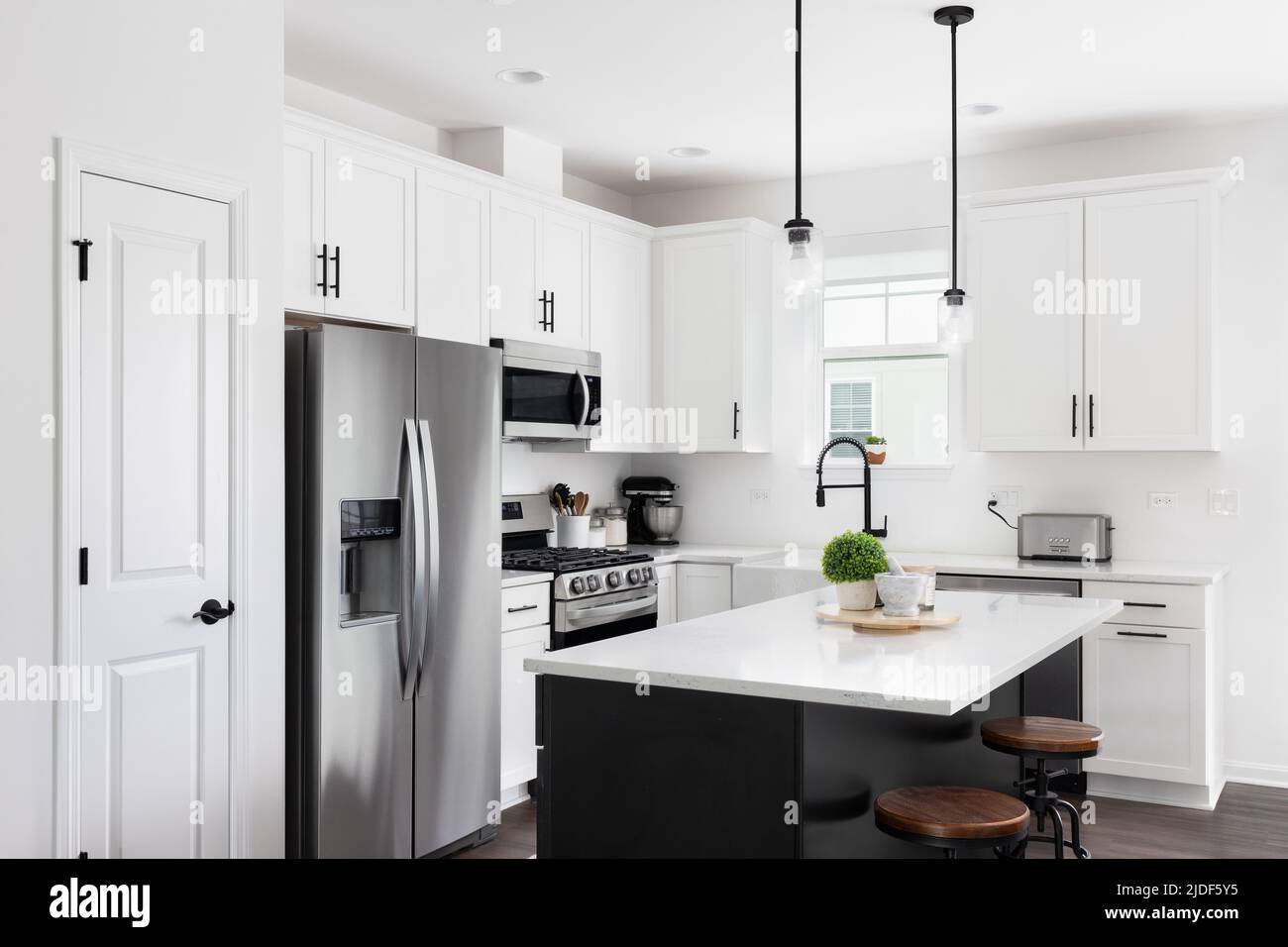A modern farmhouse kitchen with a black island, white marble