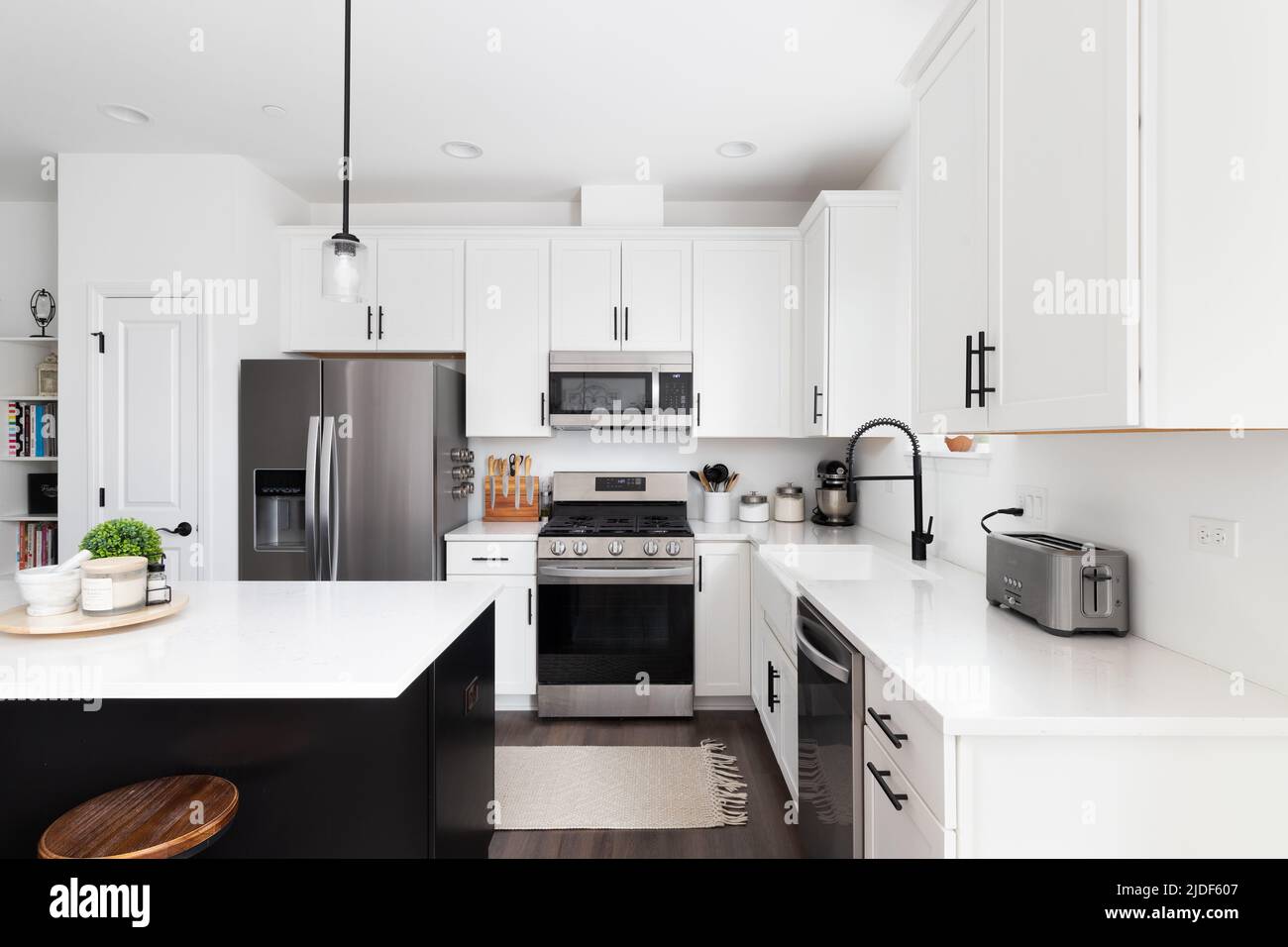 A modern farmhouse kitchen with a black island, white marble