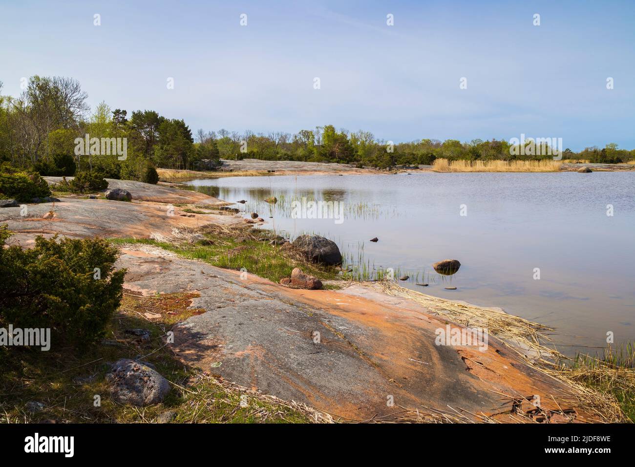 View of cliff, sea and lush shoreline along the nature trail at the Järsö nature reserve in Åland Islands, Finland, on a sunny day in the summer. Stock Photo