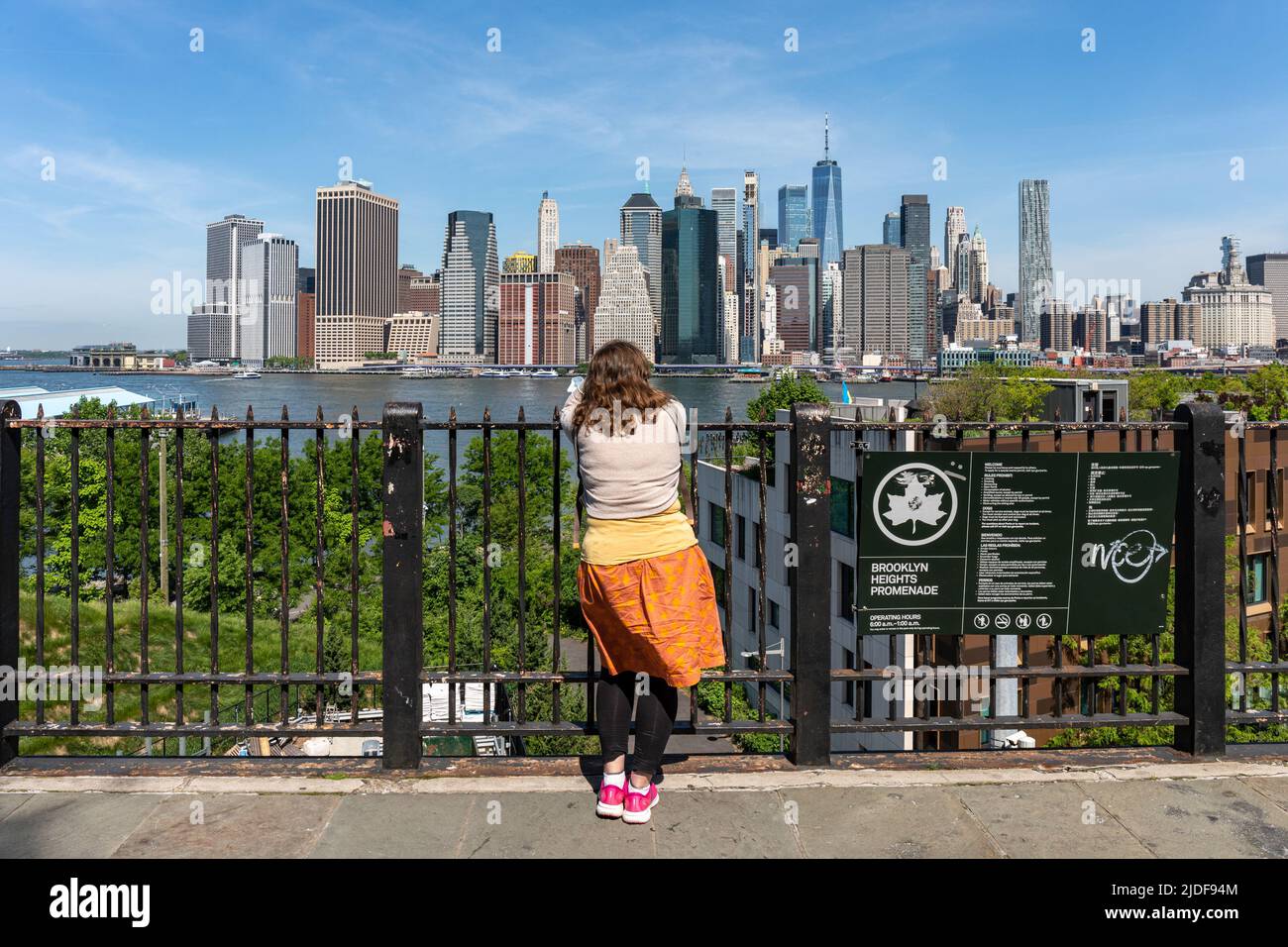 Woman looking at Lower Manhattan skyscrapers in Brooklyn Heights Promenade, New York City, United States of America Stock Photo
