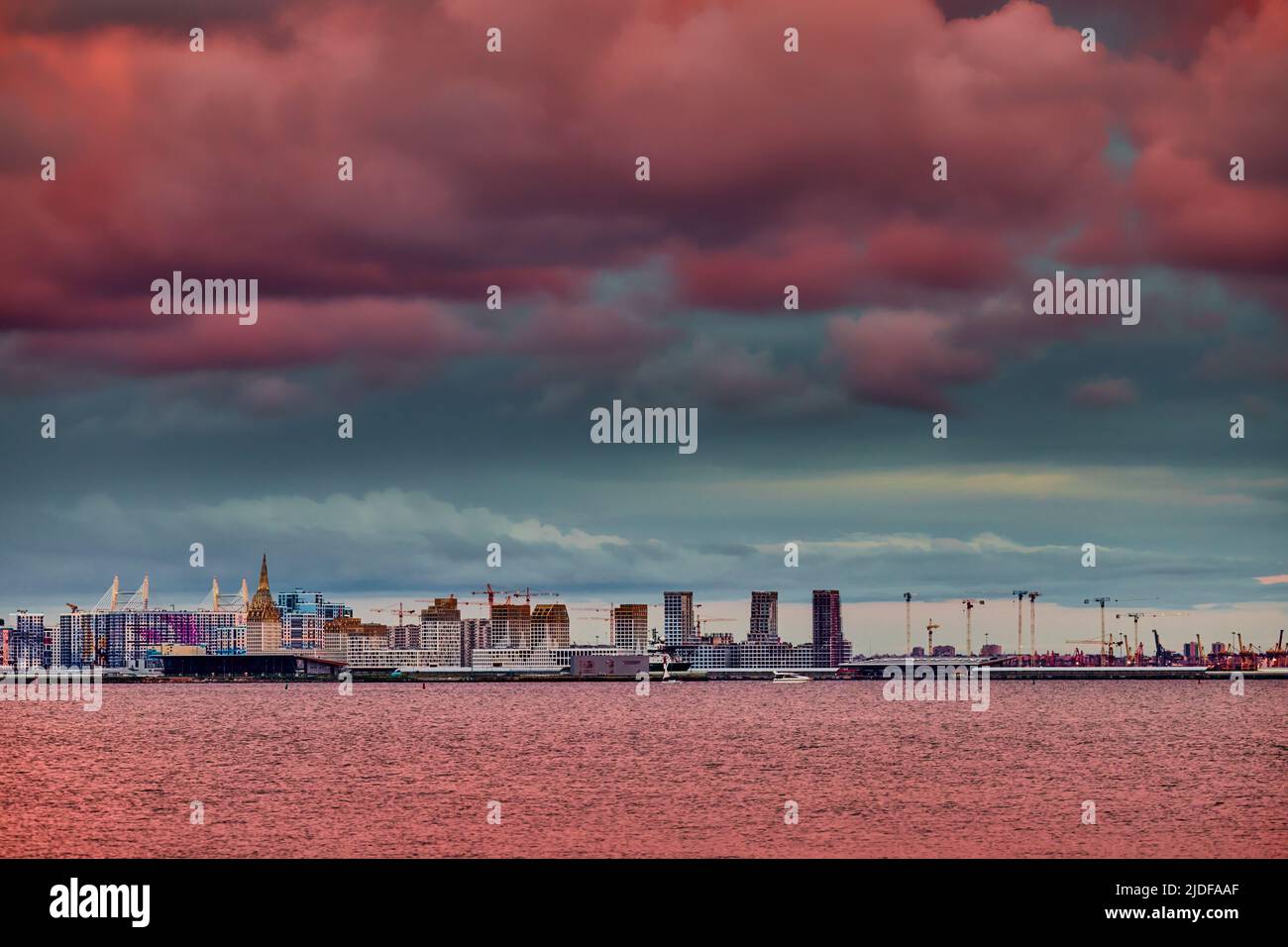 Magic pink sky over the residential complex under construction on the embankment of the Neva River on Vasilievsky island in sunset, bulk island Stock Photo