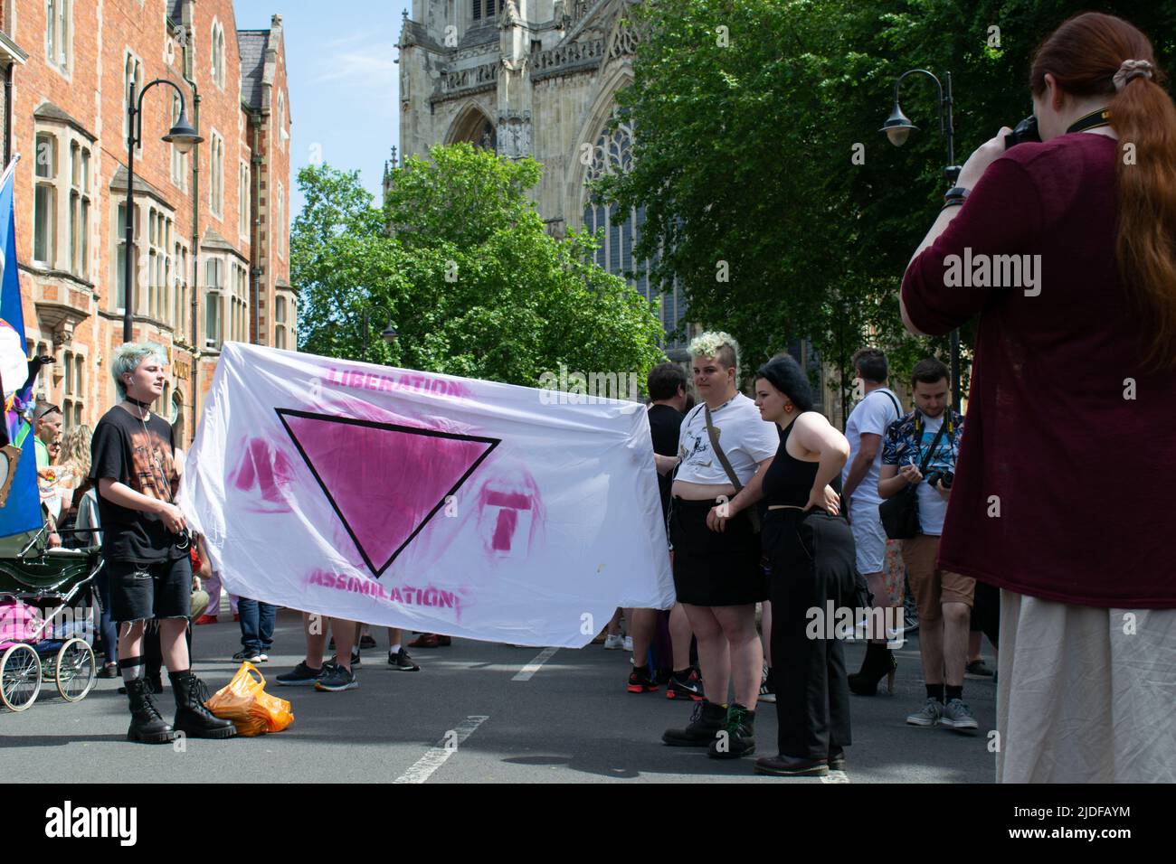 York Pride Parade. Banner with text liberation assimilation and inverted pink triangle forming word not Stock Photo