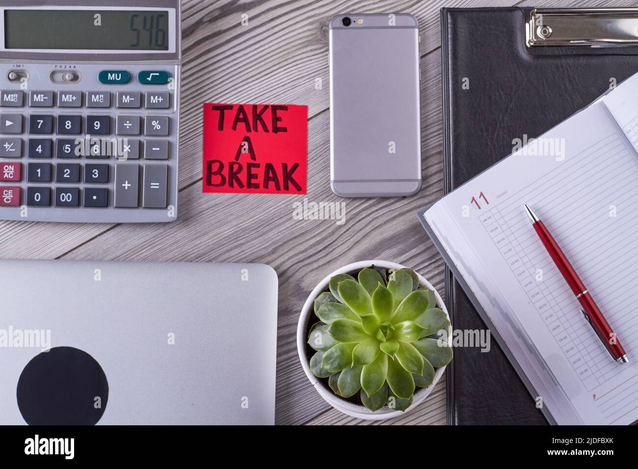 Flat lay top view office desk accessories. Take a break handwriting for hardworker. Smartphone with plant and calculator. Stock Photo