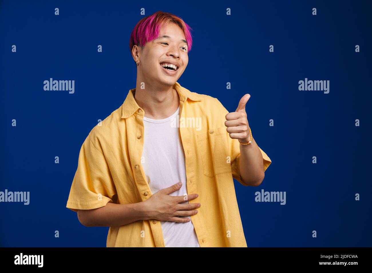 Asian boy with pink hair laughing while showing thumb up isolated over blue  background Stock Photo - Alamy