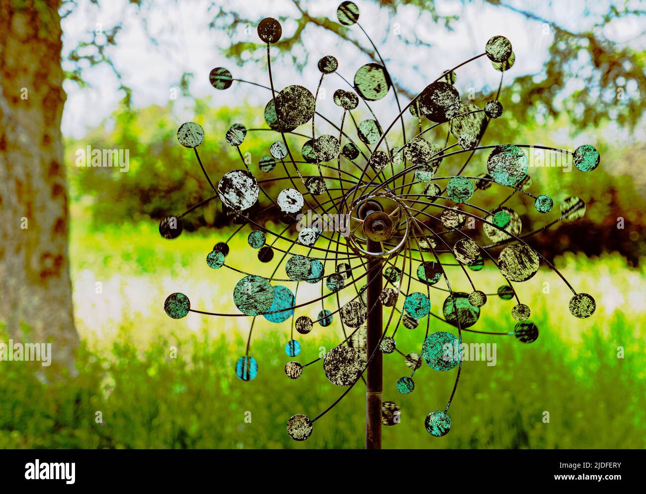 Whimsical whirligig is seen in a backyard with motion blur. Round discs turn in opposite directions with wind blowing. Stock Photo