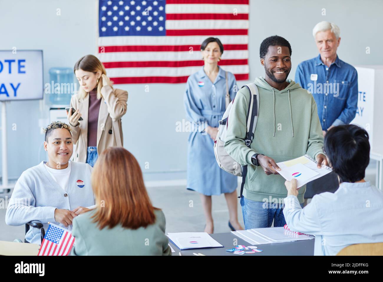 Diverse group of people in line at voting station focus on smiling ...