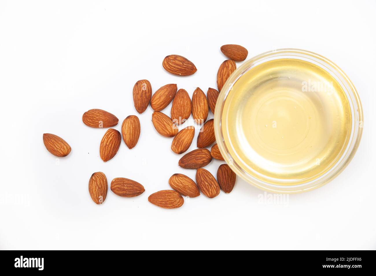 Sweet almond oil in glass bowl, first extraction, and dry almond nuts
