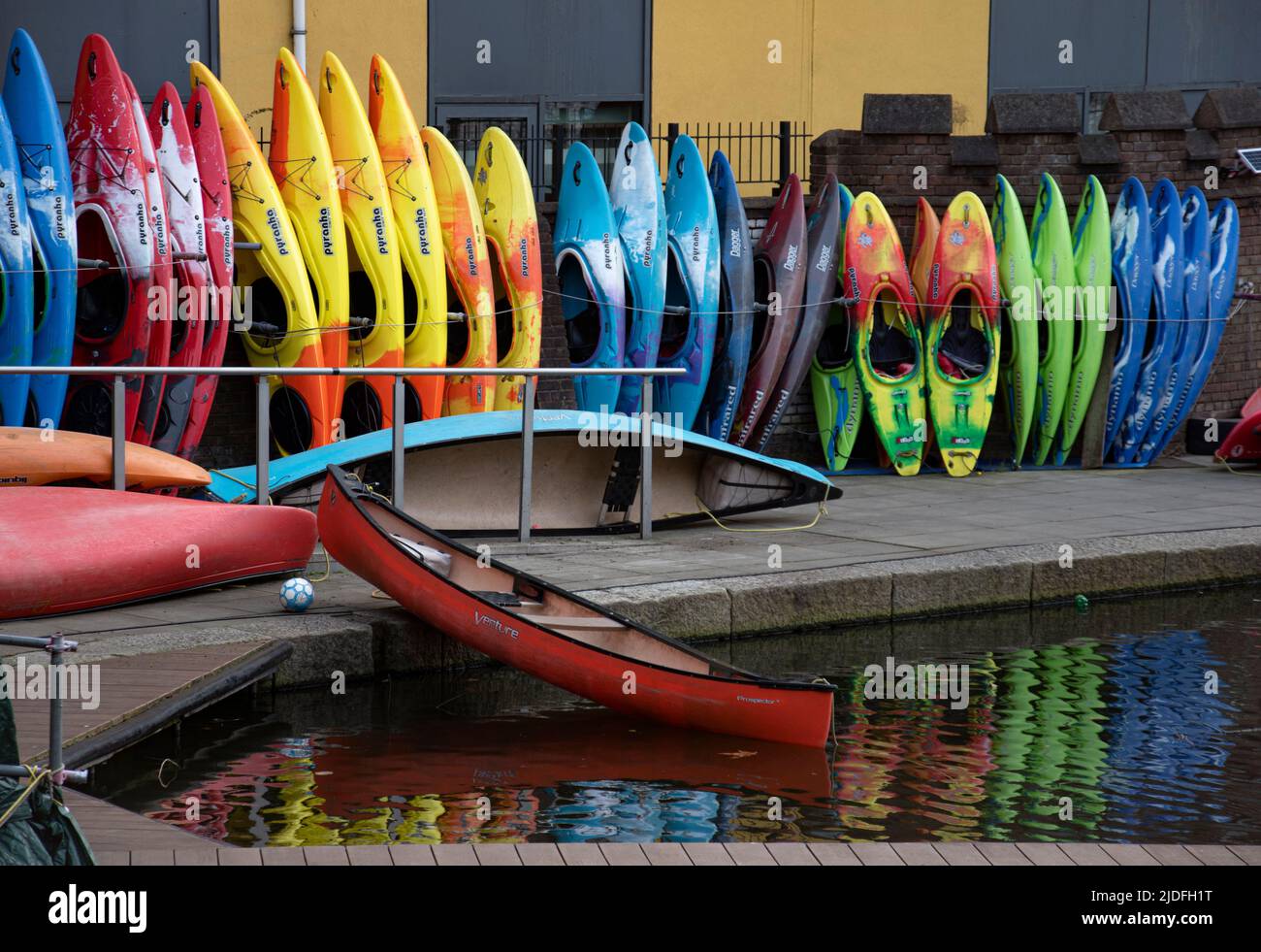 Many colorful canoes and kayaks lined up near a canal Stock Photo