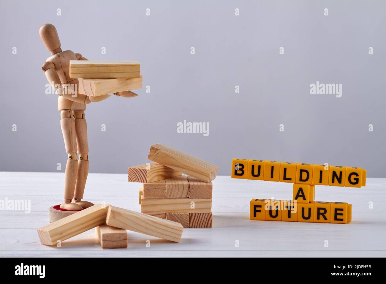 Wooden mannequin holding blocks on white background. Building a future concept. Stock Photo
