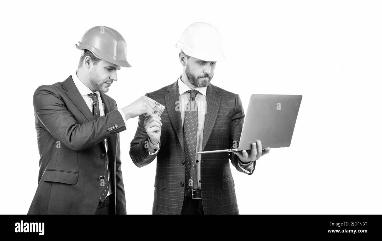business men in suit and safety helmet giving or taking money and hold computer, online fraud Stock Photo