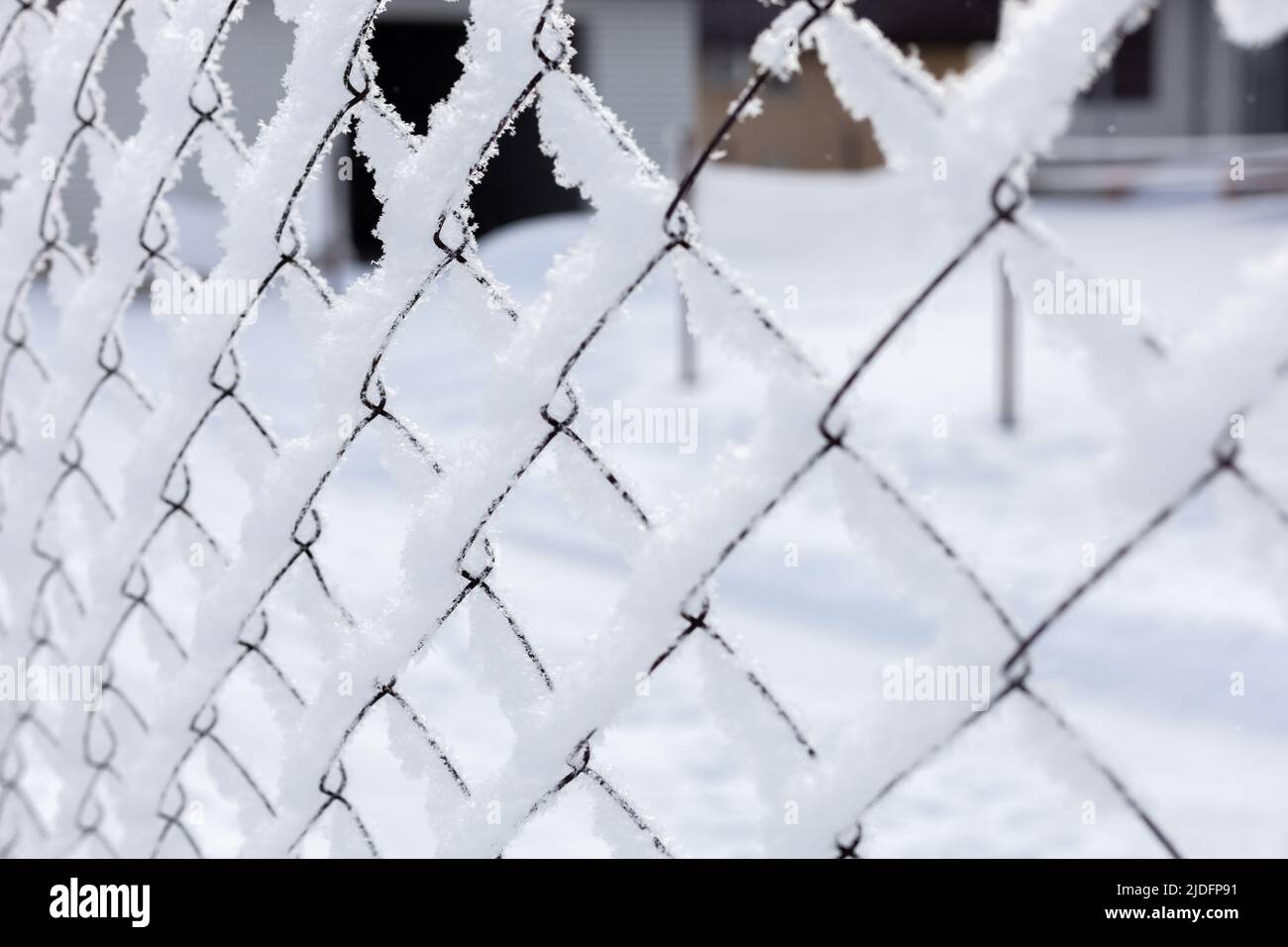 Icy mesh netting covered with snow with some building in background surrounding closed to public area. Exile to Siberia. Protests with people going Stock Photo