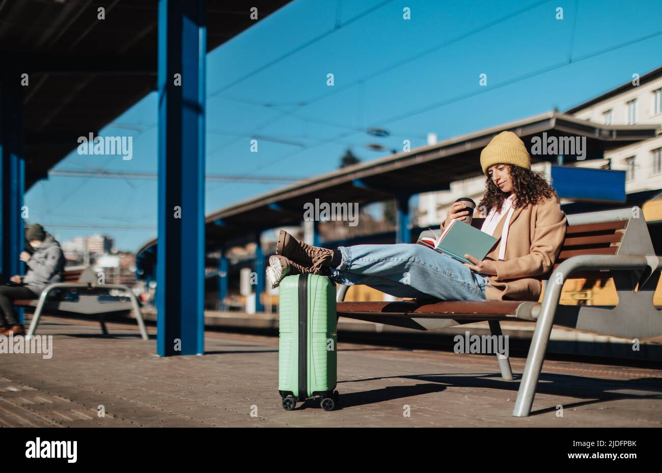 Young traveler woman sitting alone at train station platform with luggage. Stock Photo