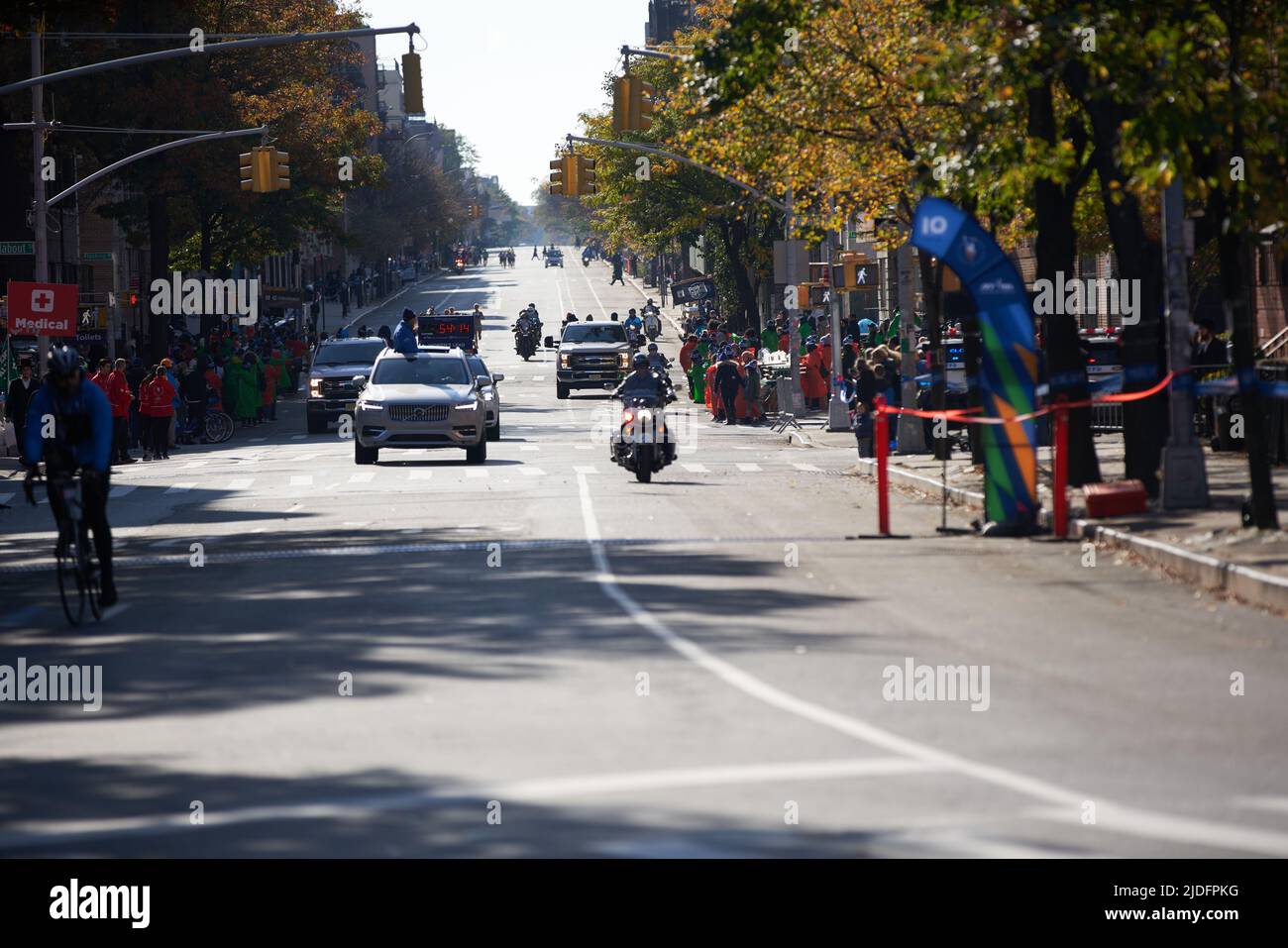 Brooklyn, New York,USA - November 3. 2019: Car with race clock in front of NYC Marathon runners. Police Motorcycle clearing streets for runners Stock Photo