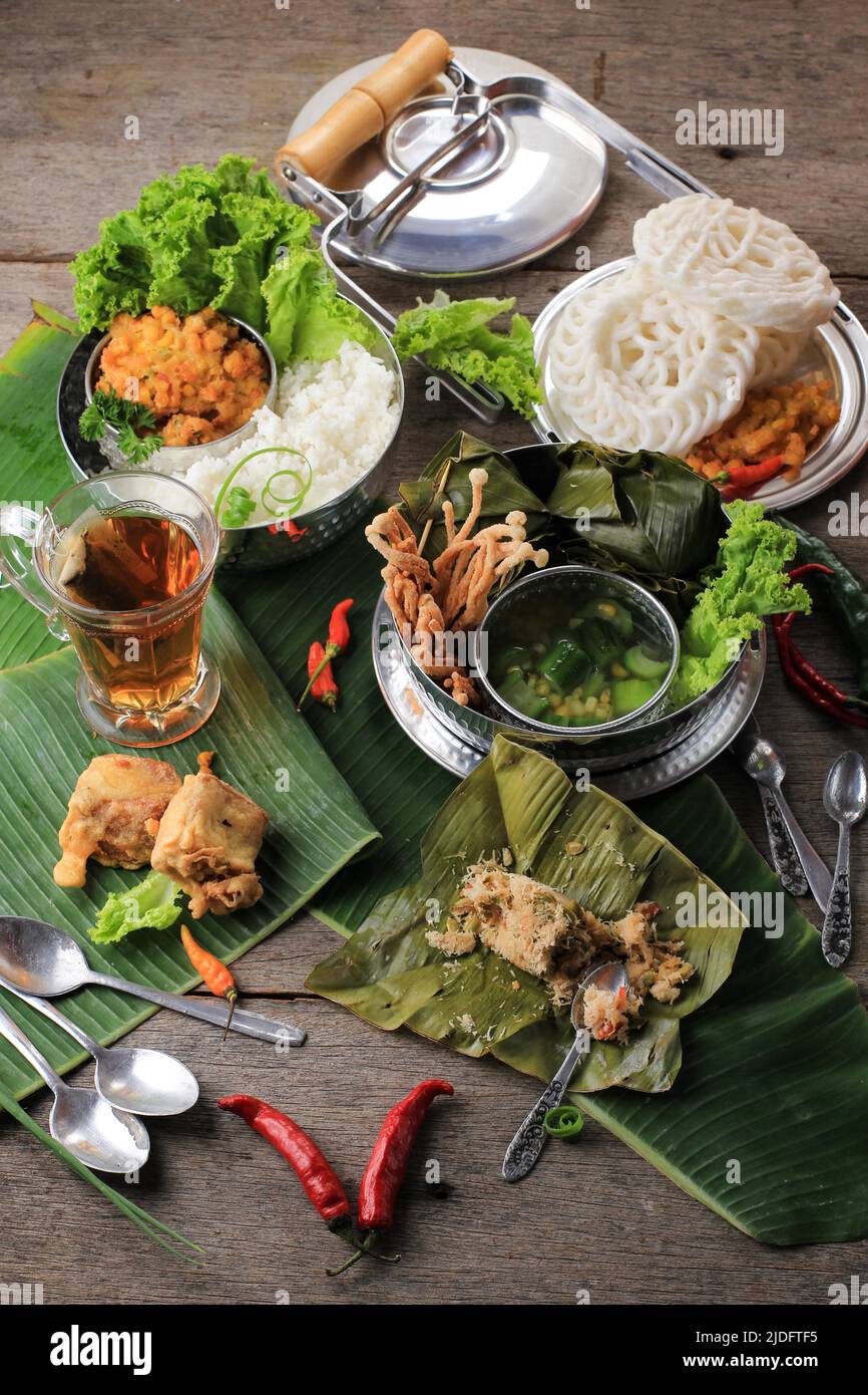 Indonesian Traditional Food for Daily Menu, Served using Rantang (Stackable Rice Box). White Rice, Spinach Soup, Corn Fritter, and Bothok Mlandingan. Stock Photo