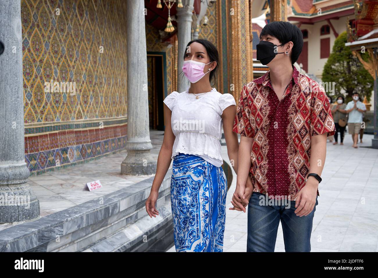 Multiethnic couple with mask visiting a buddhist temple Stock Photo