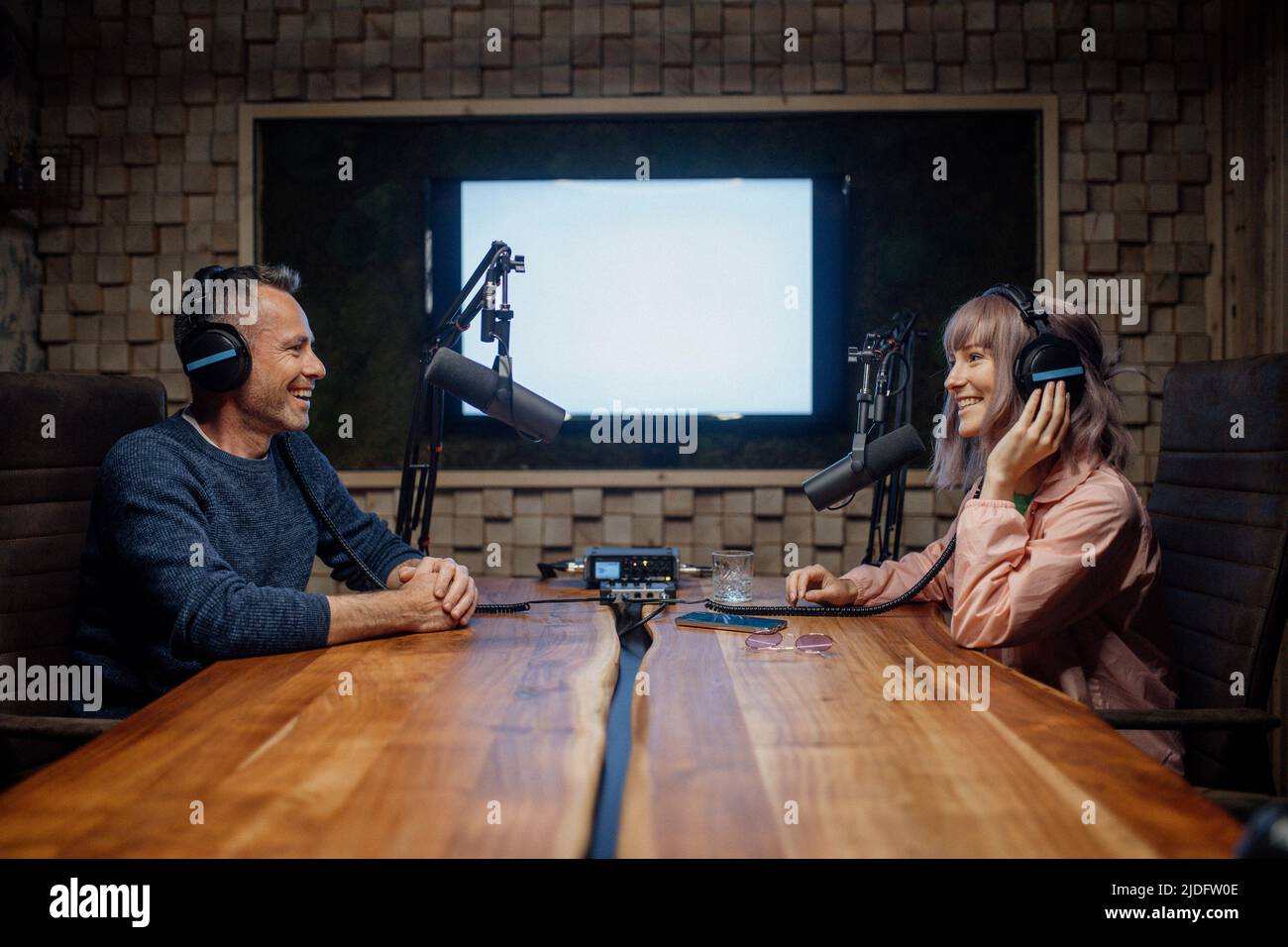 Young woman host talking to microphone and interviewing a man for a radio podcast. Stock Photo