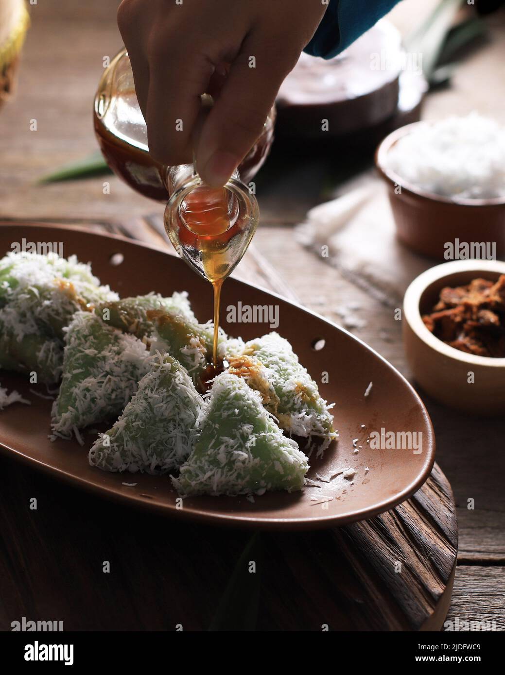 Lupis, Indonesian Traditional Snack Made From Sticky Rice, Wrapped with Banana Leaf, Shape Triangle  Served with Liquid Palm Sugar and Grated  Coconut Stock Photo