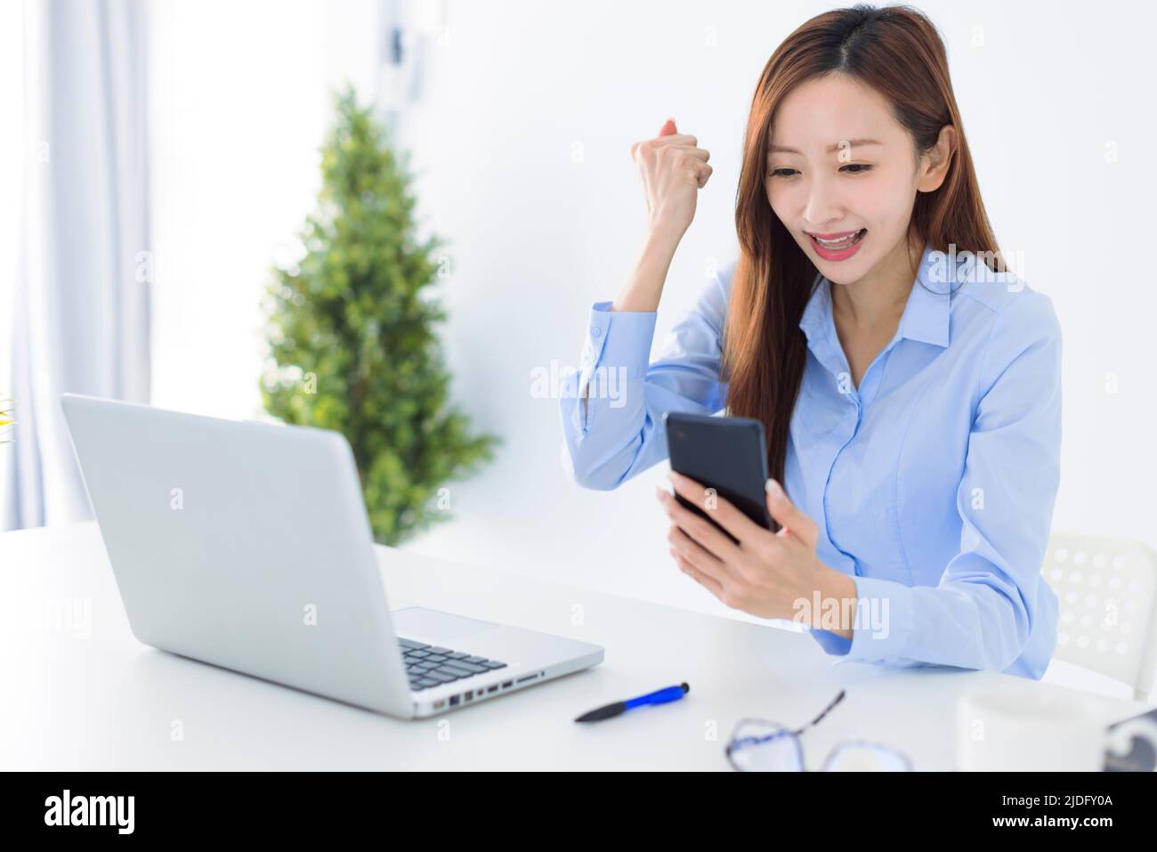 Beautiful asian woman using smartphone, exciting and celebrating with good news of business successful Stock Photo