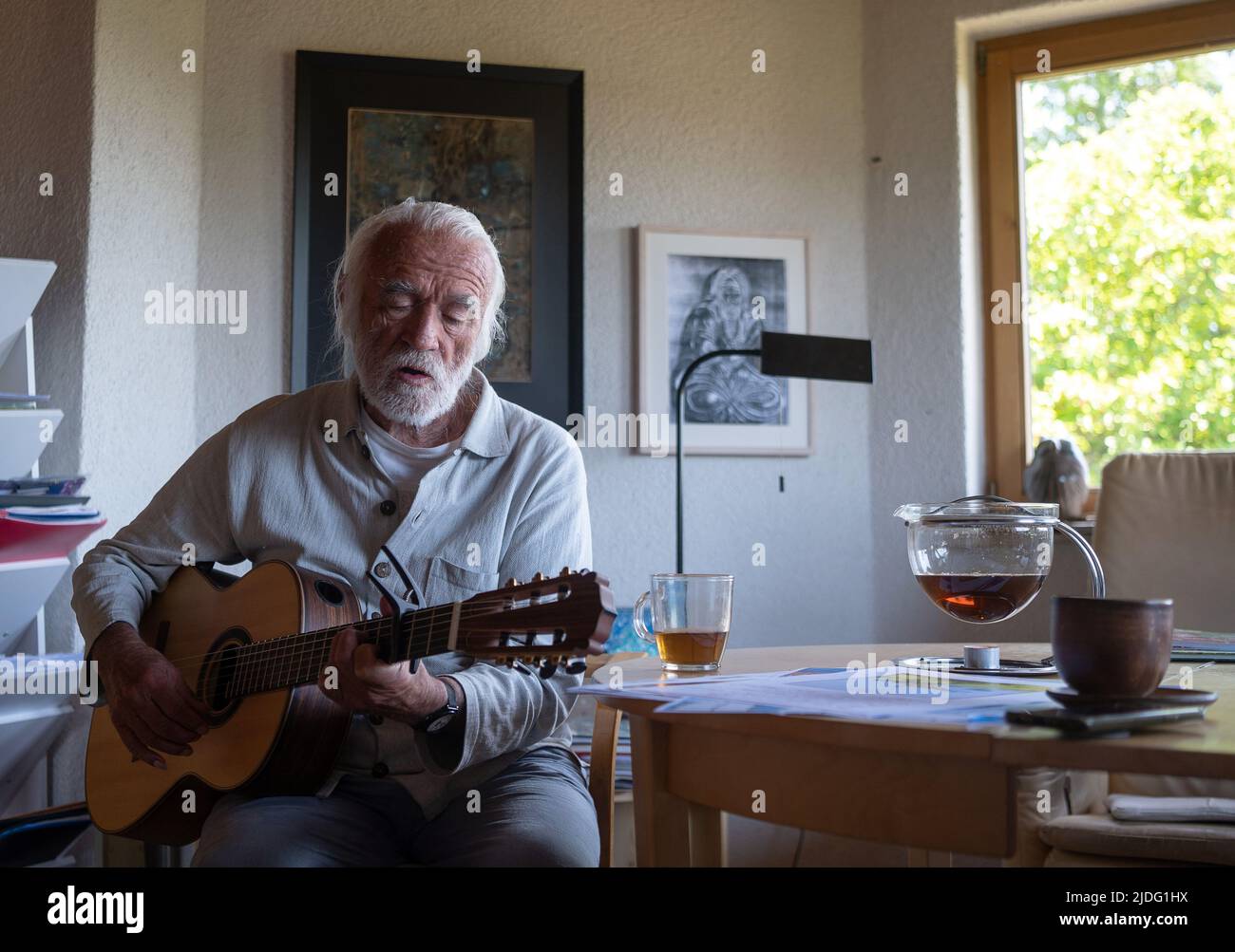Lollar, Germany. 14th June, 2022. Children's songwriter Fredrik Vahle plays guitar in his home during an interview. He celebrates his 80th birthday on June 24. (to dpa 'Songwriter Vahle: Children are hungry for cultural impulses') Credit: Sebastian Gollnow/dpa/Alamy Live News Stock Photo