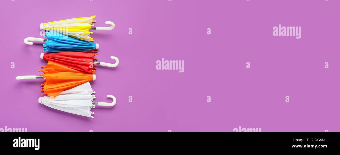 Different umbrellas on violet background with space for text Stock Photo
